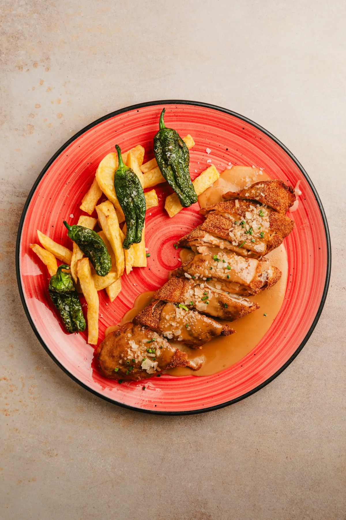 Pechuga de pollo empanada con salsa, patatas y pimientos